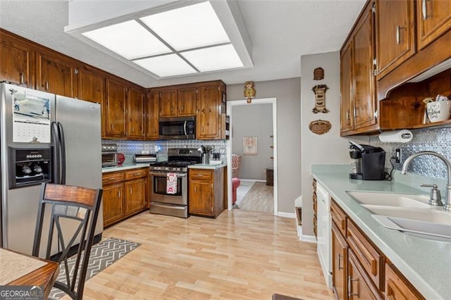 kitchen featuring appliances with stainless steel finishes, sink, backsplash, and light hardwood / wood-style flooring