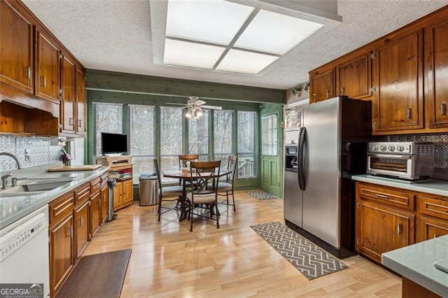 kitchen featuring sink, dishwasher, tasteful backsplash, light hardwood / wood-style floors, and stainless steel fridge with ice dispenser