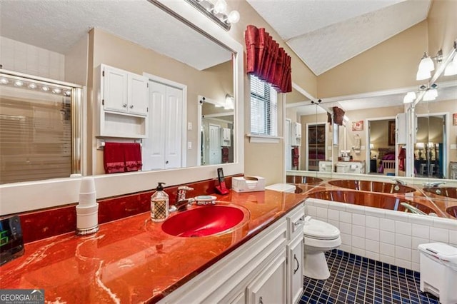 bathroom with vanity, a textured ceiling, vaulted ceiling, tile patterned floors, and toilet