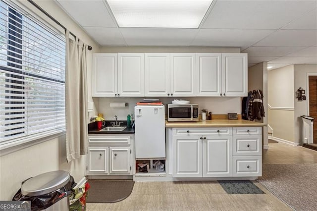 kitchen with a drop ceiling, sink, and white cabinets