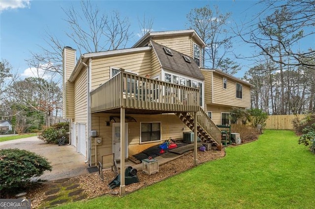 rear view of property with a wooden deck, a garage, central AC, and a lawn