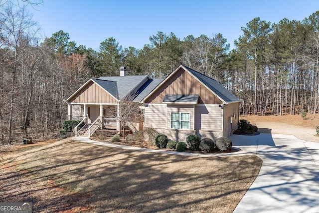 craftsman-style home featuring board and batten siding, covered porch, a shingled roof, and a chimney