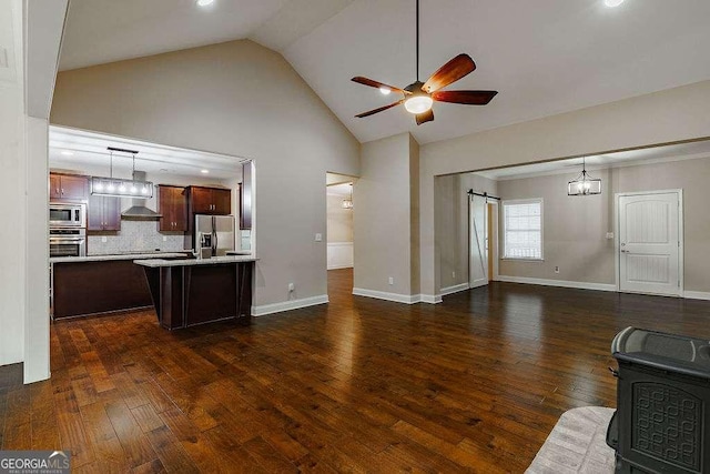 living room with a ceiling fan, dark wood-type flooring, baseboards, and a barn door