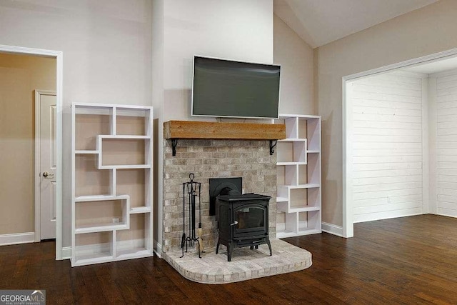 unfurnished living room with vaulted ceiling, dark wood finished floors, a wood stove, and baseboards