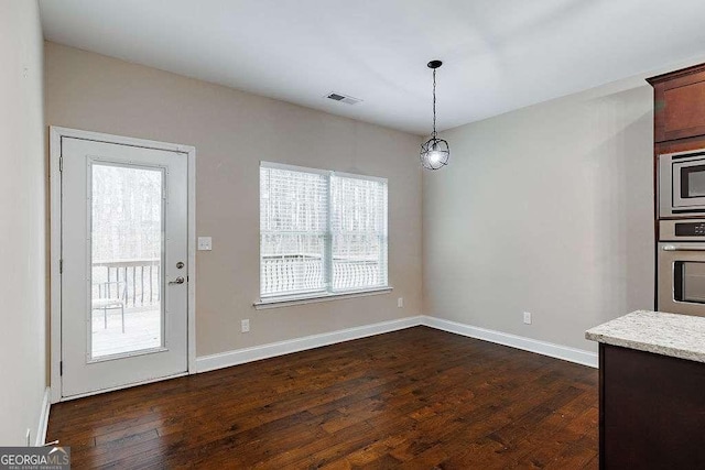 unfurnished dining area with dark wood finished floors, visible vents, and baseboards