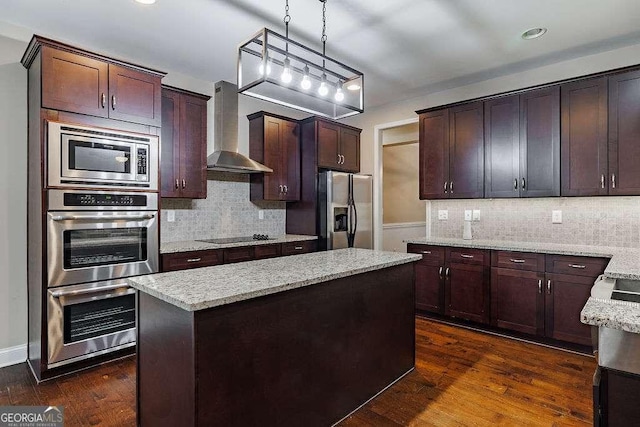 kitchen featuring stainless steel appliances, hanging light fixtures, dark wood-type flooring, a kitchen island, and wall chimney range hood