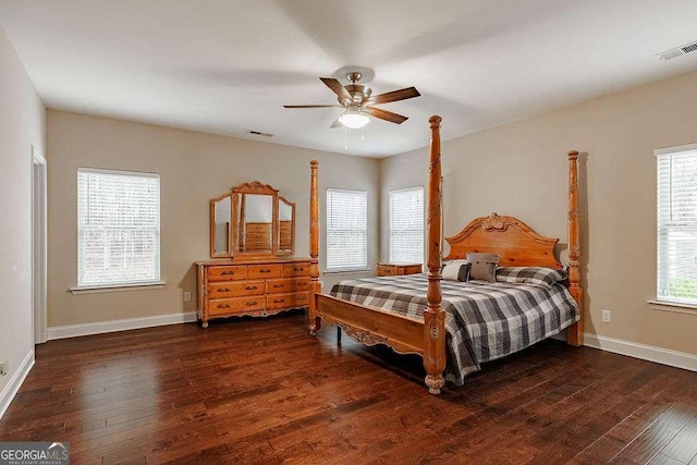 bedroom featuring dark wood-style floors, visible vents, baseboards, and a ceiling fan