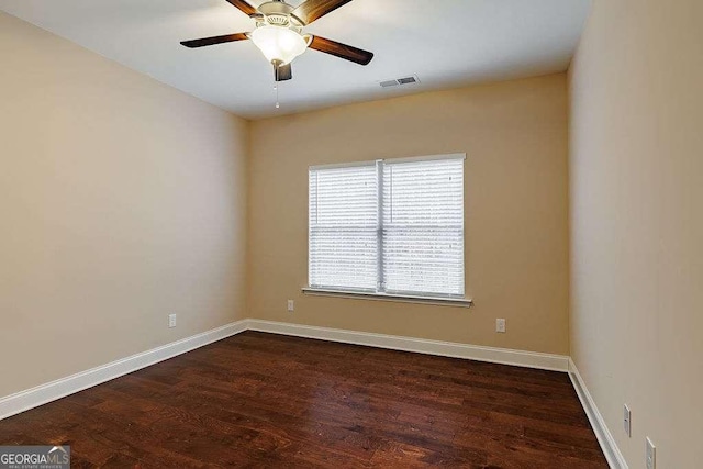 spare room featuring dark wood-type flooring, visible vents, ceiling fan, and baseboards