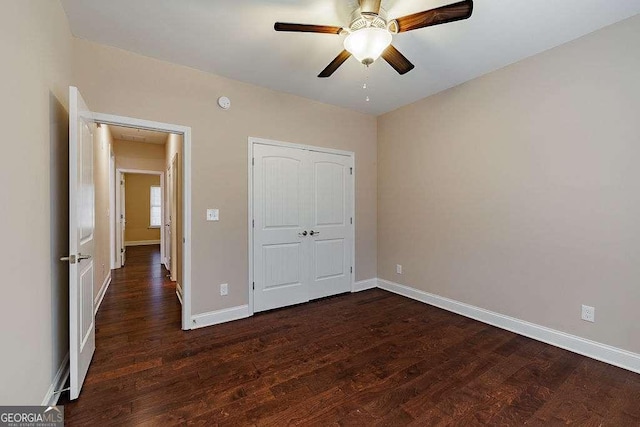 unfurnished bedroom with a ceiling fan, a closet, baseboards, and dark wood-style flooring