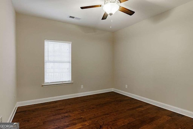 empty room featuring visible vents, dark wood finished floors, baseboards, and ceiling fan