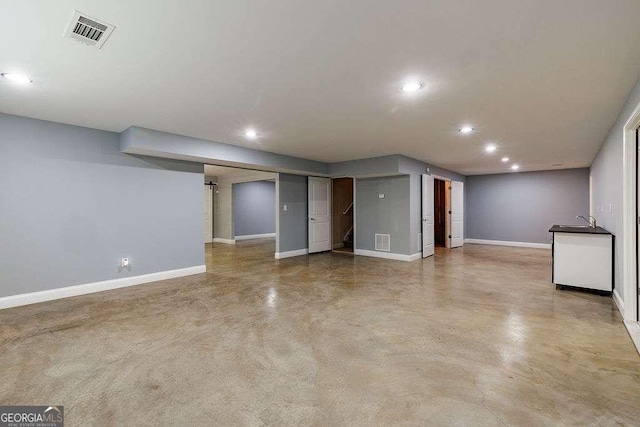 finished basement featuring baseboards, visible vents, a sink, and recessed lighting