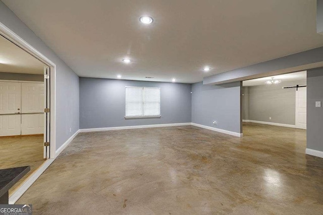 basement with recessed lighting, baseboards, and a barn door