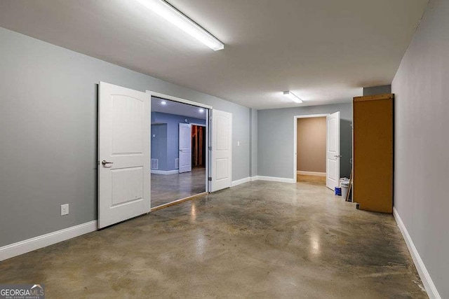 spare room featuring concrete floors and baseboards