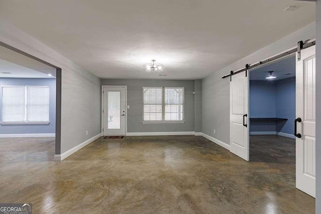 foyer entrance featuring an inviting chandelier, a barn door, concrete floors, and baseboards