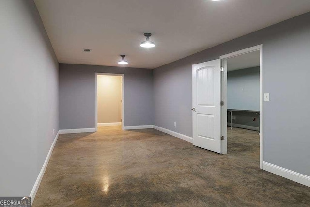 empty room featuring concrete floors, visible vents, and baseboards