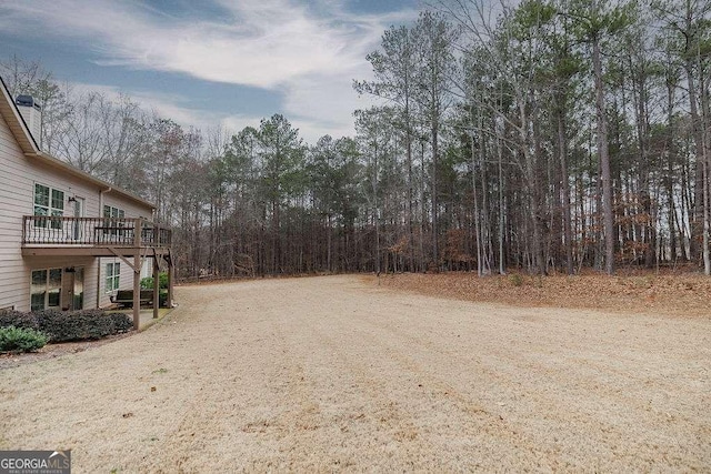 view of yard with a wooden deck and dirt driveway