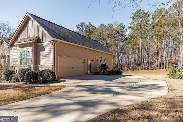 view of side of property featuring roof with shingles, driveway, and an attached garage