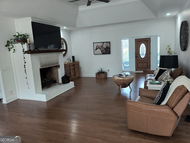 living room with ornamental molding, dark wood-type flooring, ceiling fan, and a fireplace