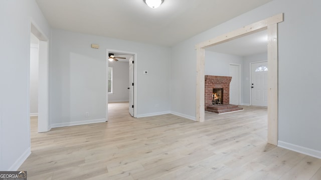 unfurnished living room featuring ceiling fan, a fireplace, and light hardwood / wood-style flooring