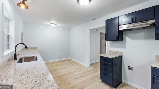 kitchen featuring light stone counters, sink, and light wood-type flooring