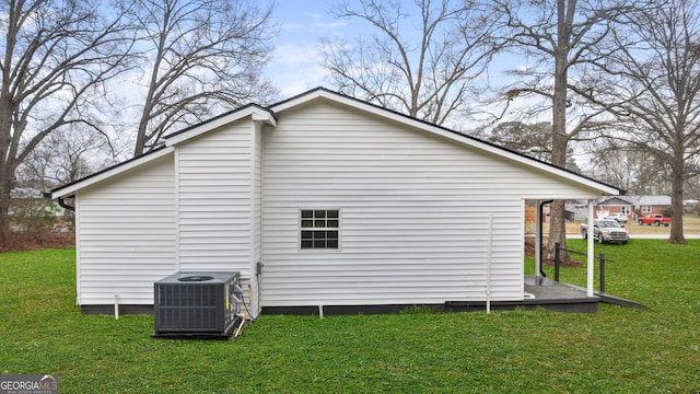 view of side of property with central AC and a lawn