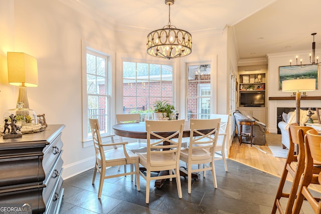 dining space with a healthy amount of sunlight, ornamental molding, and a notable chandelier