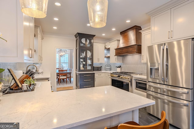 kitchen featuring appliances with stainless steel finishes, decorative light fixtures, a kitchen bar, and custom range hood