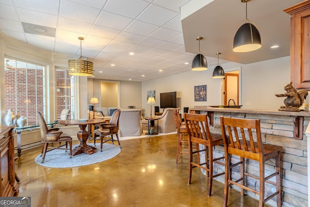 dining area featuring a drop ceiling and concrete flooring