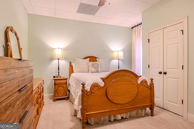 carpeted bedroom featuring ceiling fan, a closet, and a drop ceiling