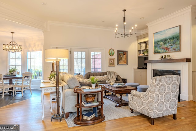 living room with crown molding, a chandelier, and light hardwood / wood-style flooring