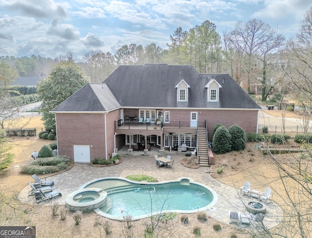 rear view of property with a pool with hot tub, a patio, and an outdoor fire pit