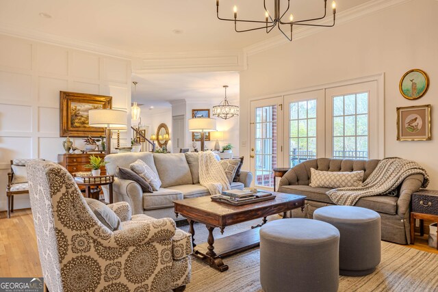 living room with ornamental molding, a notable chandelier, and light wood-type flooring