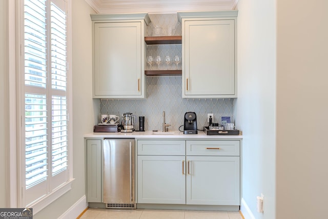 bar featuring crown molding, refrigerator, sink, and decorative backsplash