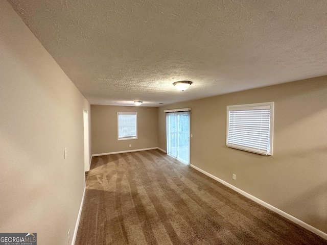 carpeted empty room featuring a textured ceiling