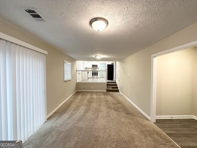 hallway featuring a textured ceiling and dark colored carpet