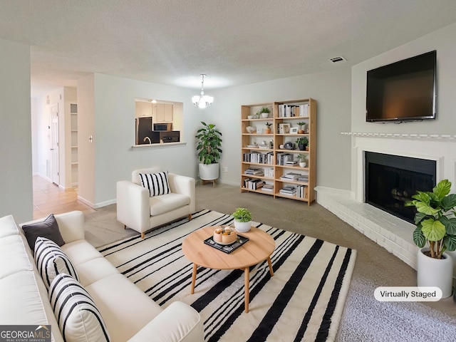 carpeted living room featuring an inviting chandelier, a fireplace, and a textured ceiling