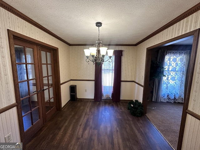 unfurnished dining area featuring dark hardwood / wood-style flooring, a chandelier, french doors, and a textured ceiling