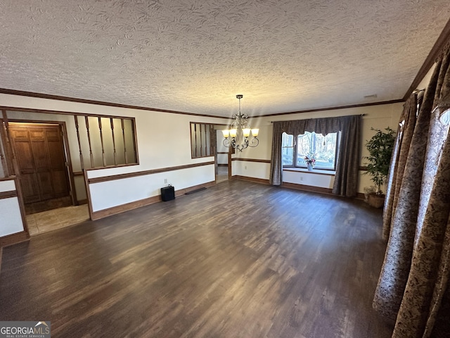 unfurnished dining area with ornamental molding, dark wood-type flooring, a notable chandelier, and a textured ceiling