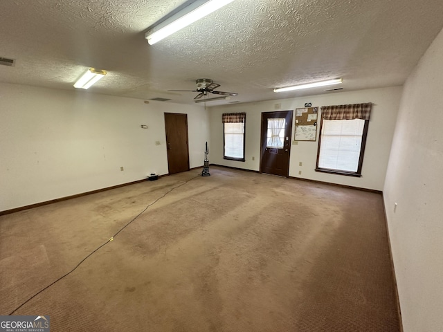 carpeted empty room with ceiling fan and a textured ceiling