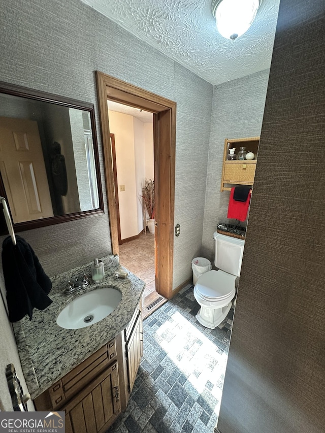 bathroom featuring vanity, a textured ceiling, and toilet