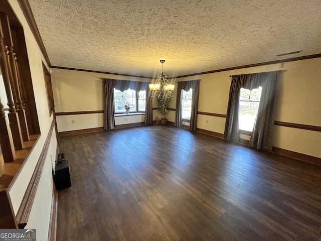 unfurnished room with dark hardwood / wood-style flooring, a notable chandelier, crown molding, and a wealth of natural light