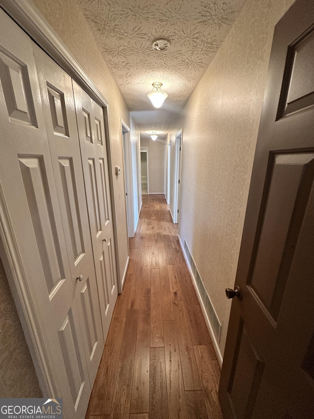 hall featuring a textured ceiling and dark hardwood / wood-style flooring