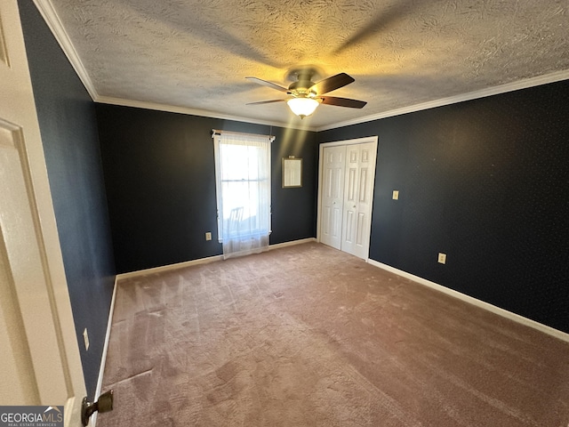 unfurnished bedroom with ornamental molding, a closet, a textured ceiling, and carpet