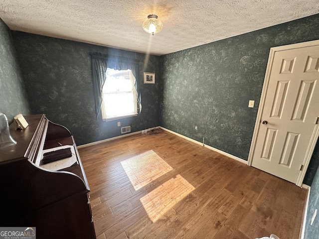 unfurnished room with hardwood / wood-style flooring and a textured ceiling