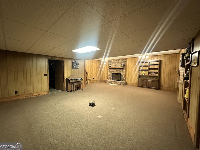 basement with a stone fireplace, wooden walls, a paneled ceiling, and carpet