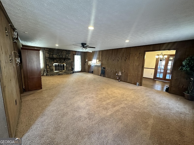 unfurnished living room featuring ceiling fan, carpet, a fireplace, a textured ceiling, and french doors