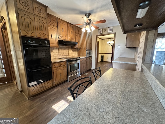 kitchen with a breakfast bar area, backsplash, stainless steel appliances, dark hardwood / wood-style floors, and ceiling fan with notable chandelier