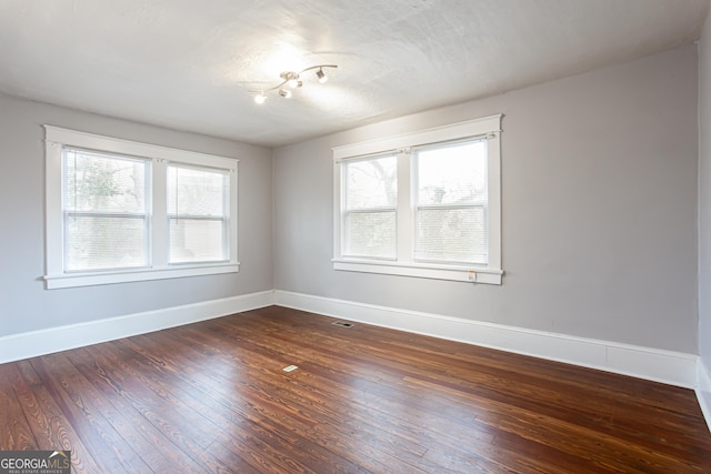 unfurnished room with dark wood-type flooring and a textured ceiling