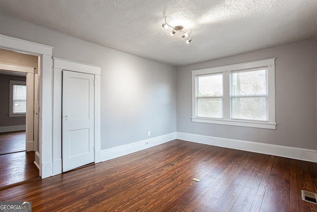 empty room with dark hardwood / wood-style floors and a textured ceiling