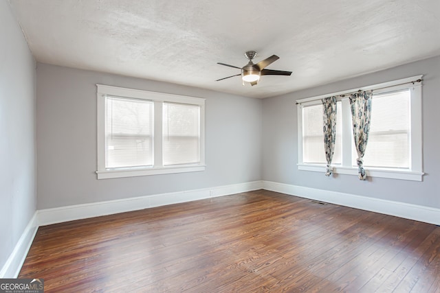 empty room with ceiling fan, dark hardwood / wood-style floors, and a textured ceiling